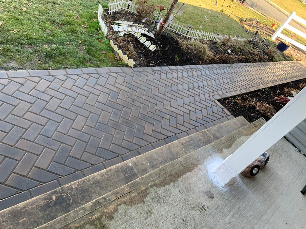 Dark paver driveway and landing meeting a poured concrete pad