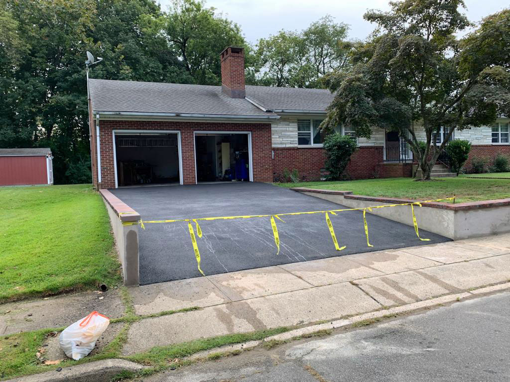 New asphalt driveway running between low concrete retaining walls