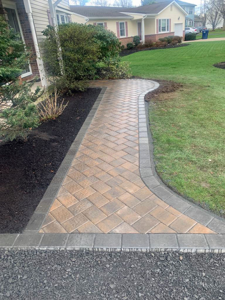 Herringbone paver walkway in tan and brown with a curved border
