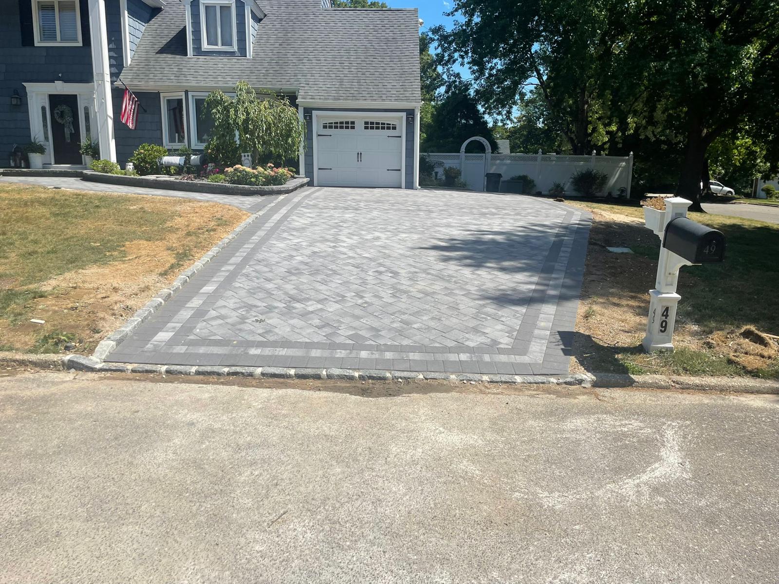 Gray paver driveway with a double charcoal border and cobblestone street apron