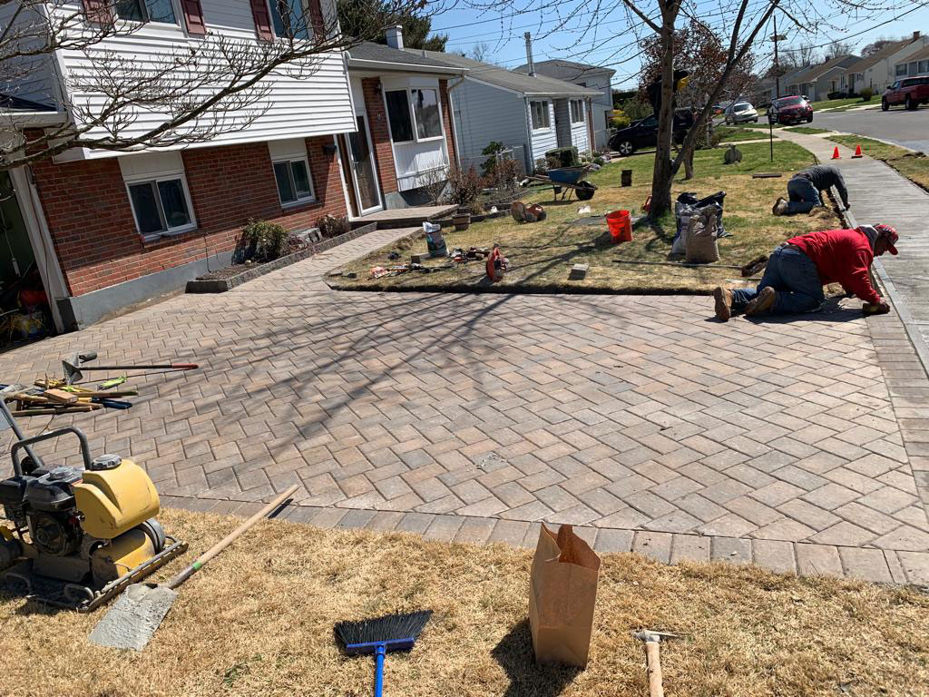 Crew compacting a brick paver walkway during installation