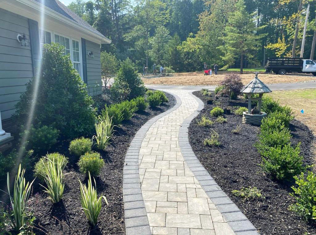 Curved light-stone paver walkway winding through fresh landscaping