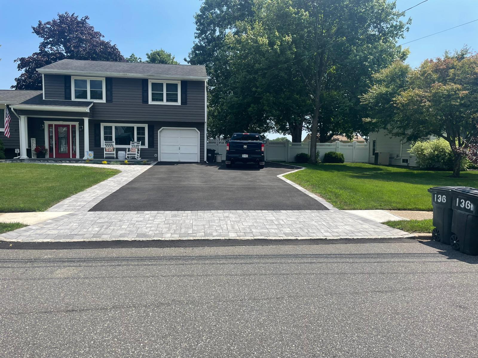 Asphalt driveway finished with a wide paver apron at the street