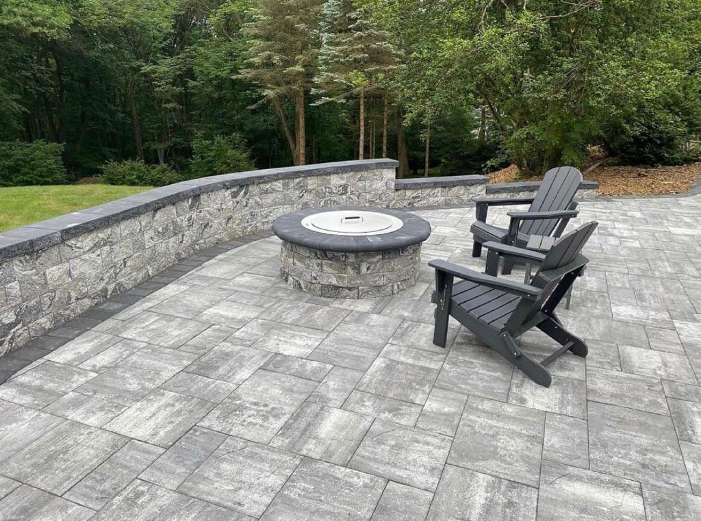 Bluestone paver patio with a stone fire pit and seating wall built by MH Paving & Masonry