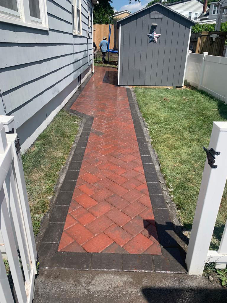 Red brick herringbone side walkway with a charcoal paver border