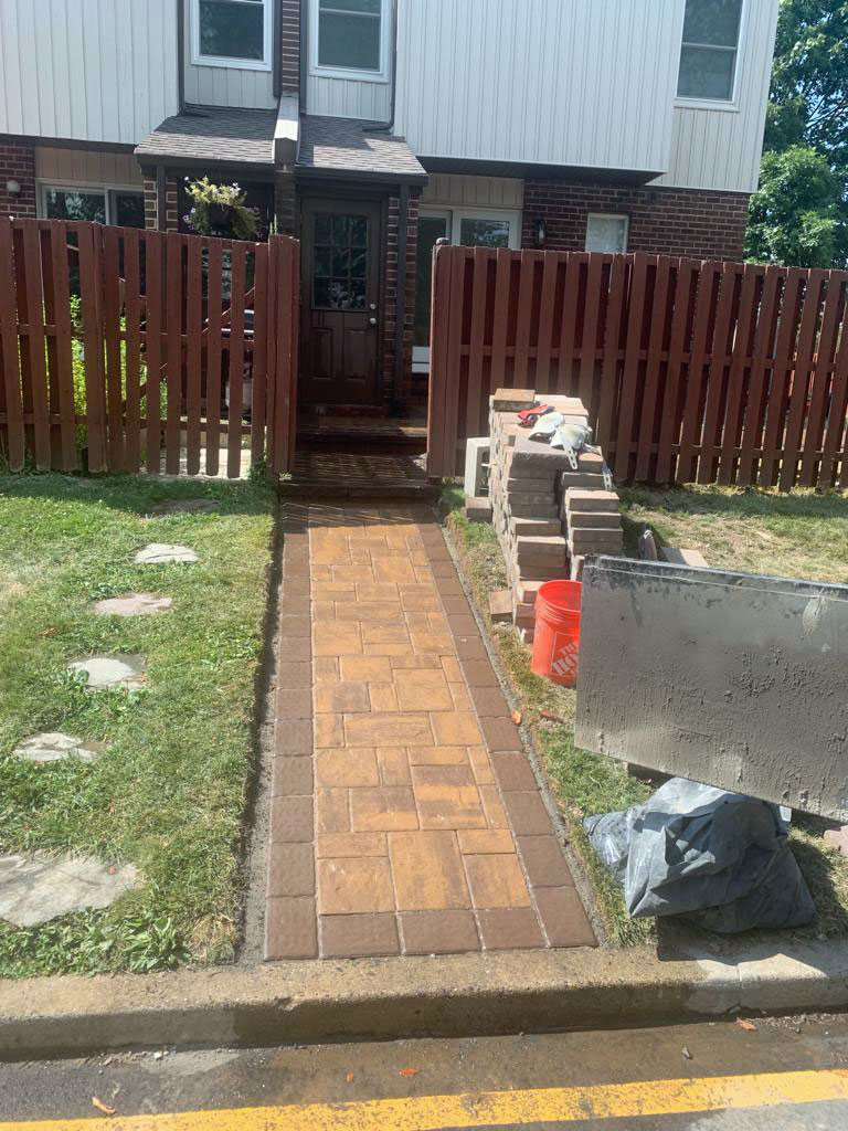 Brick paver walkway leading to a front stoop, mid-installation