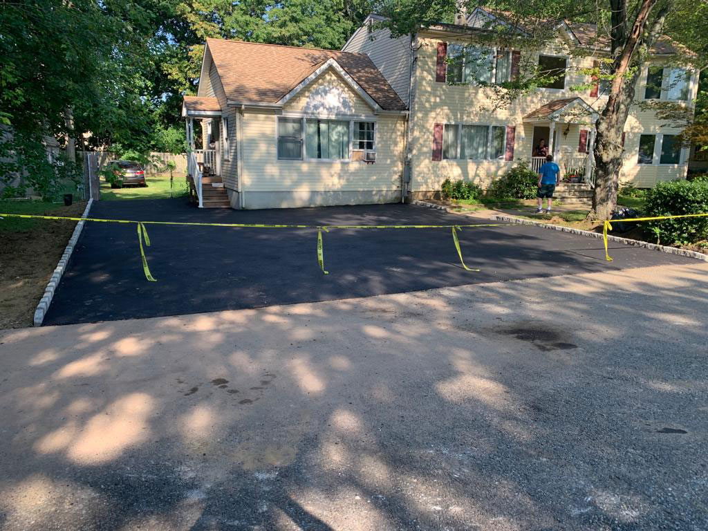 Freshly paved wide asphalt parking area with stone edging
