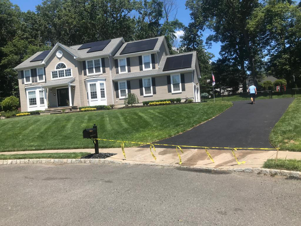 Freshly paved asphalt driveway at a large colonial home