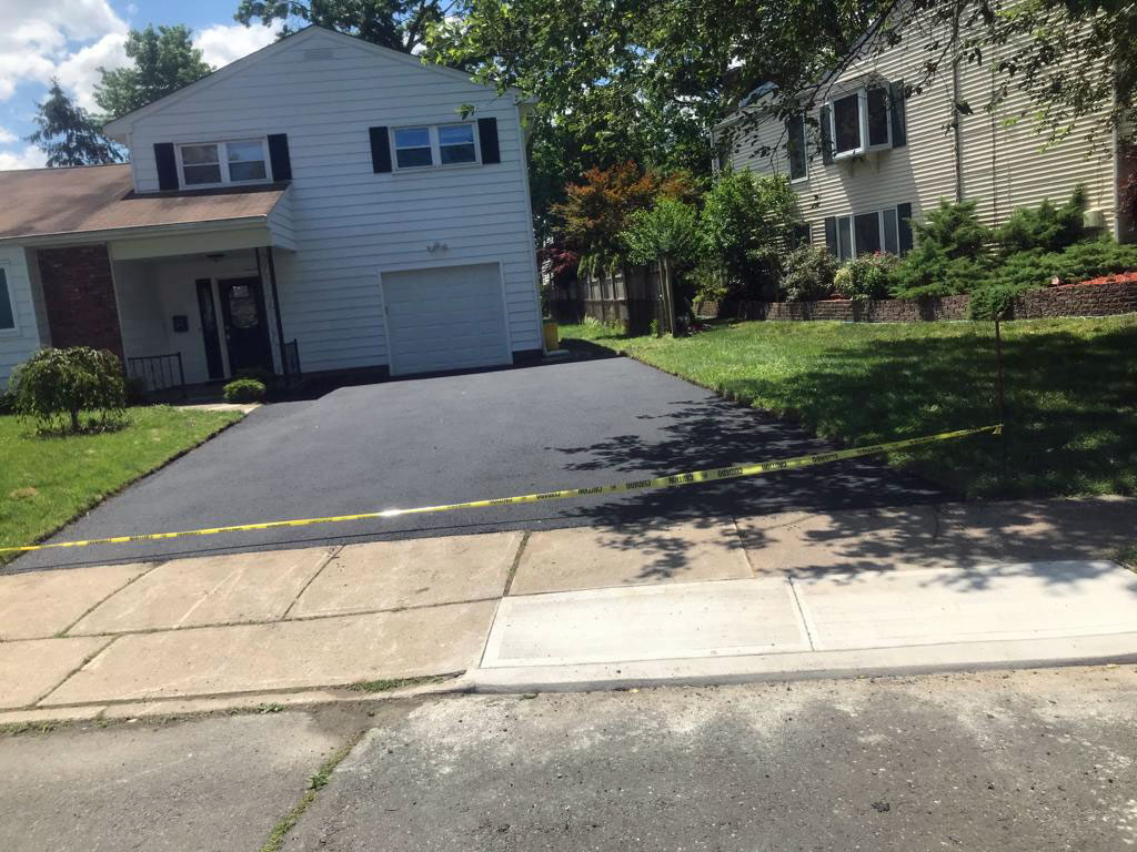 New asphalt driveway tied into a concrete sidewalk apron